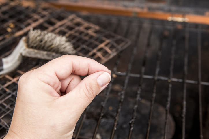 A person holding a hair above a grill