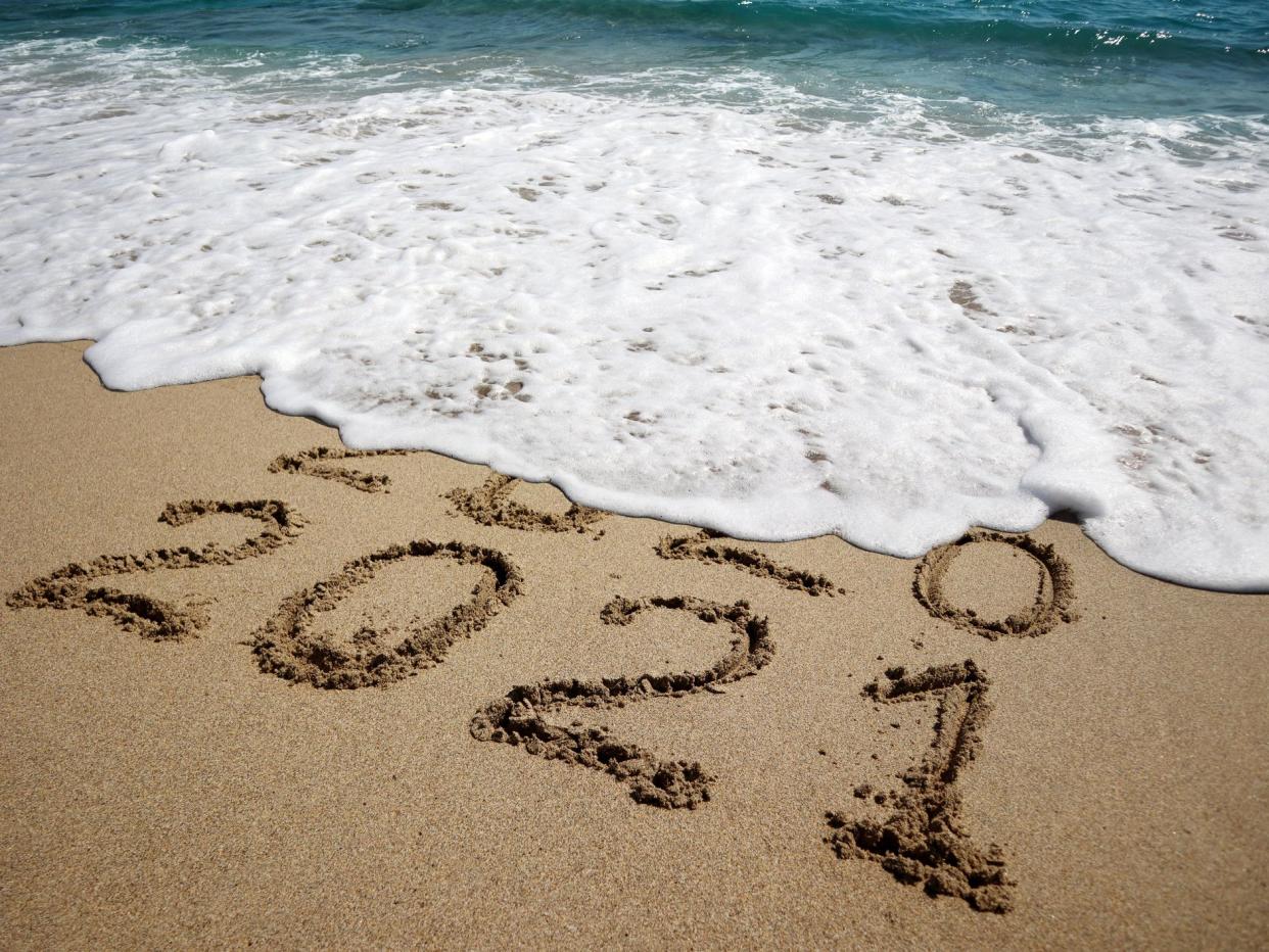 New year 2021 and old year 2020 written on sandy beach with waves