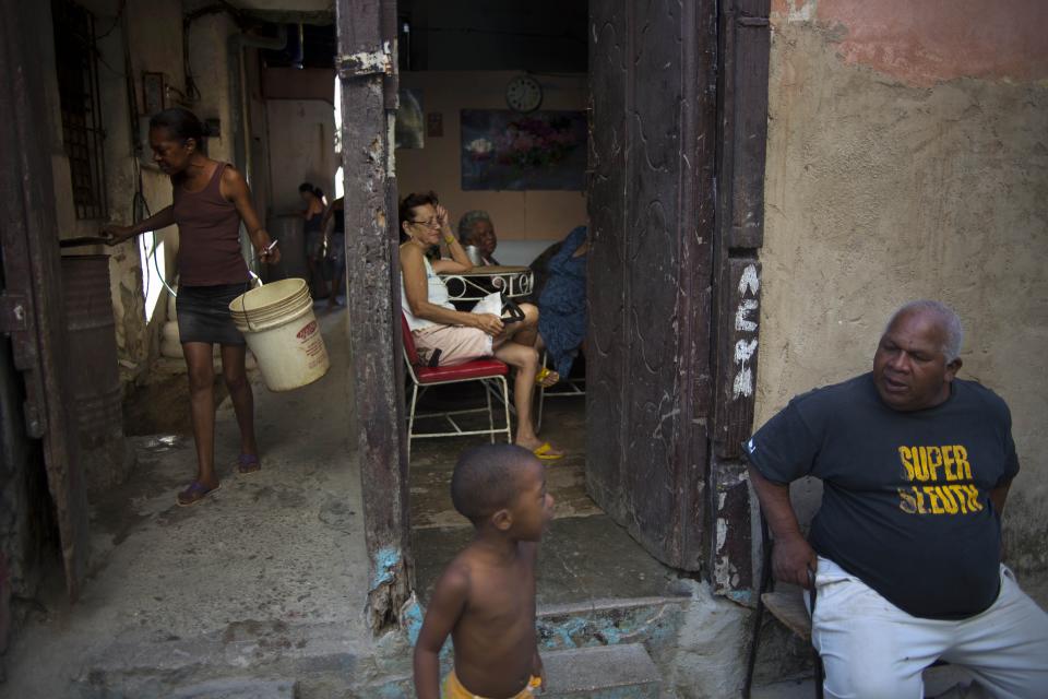 In this April 12, 2014 photo, people talk on the doorstep of their house in Havana, Cuba. Official government statistics show new construction has actually declined since Raul Castro assumed the presidency from his older brother Fidel in 2008. (AP Photo/Ramon Espinosa)