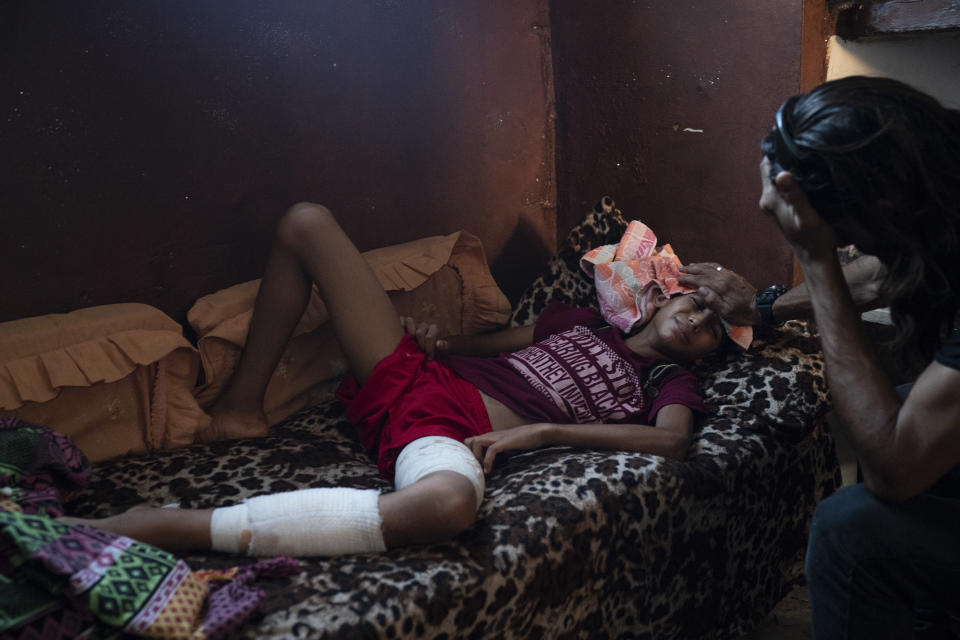 In this Sept. 12, 2018, photo, Raed Abu Khader, right, holds a wet cloth on the forehead of his 12-year-old son Mohammed in Gaza City. Mohammed was shot in the leg at one of the demonstrations on Gaza strip's border with Israel. Ever since Hamas launched demonstrations in March against Israel's blockade of Gaza, children have been a constant presence in the crowds. Since then, U.N. figures show that 948 children under 18 have been shot by Israeli forces and 2,295 have been hospitalized, including 17 who have had a limb amputated. (AP Photo/Felipe Dana)