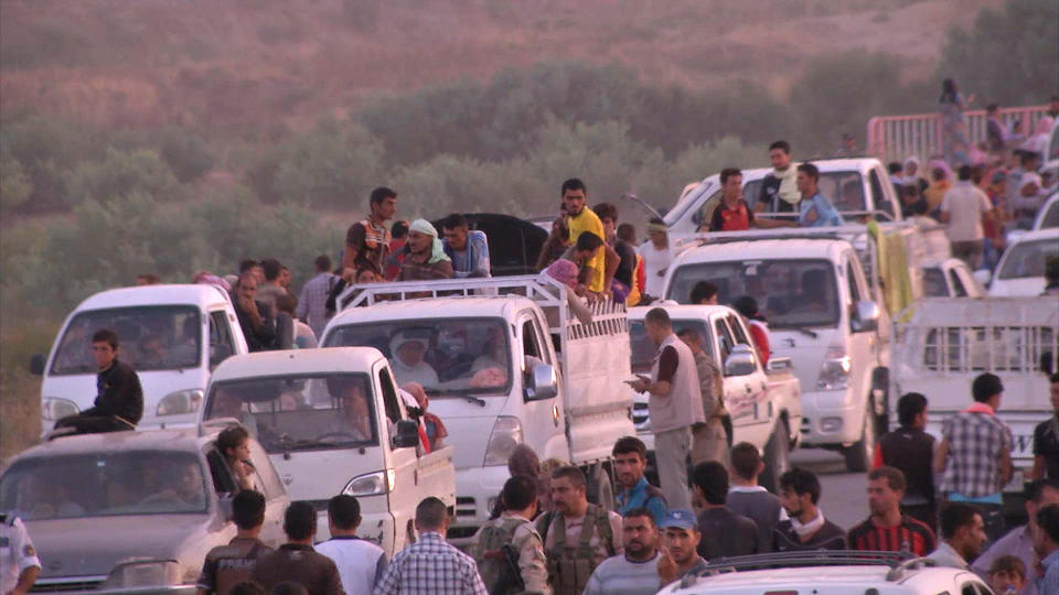 This image made from video taken on Sunday, Aug. 3, 2014 shows Iraqis people from the Yazidi community arriving in Irbil in northern Iraq after Islamic militants attacked the towns of Sinjar and Zunmar. Around 40 thousand people crossed the bridge of Shela in Fishkhabur into the Northern Kurdish Region of Iraq, after being given an ultimatum by Islamic militants to either convert to Islam, pay a security tax, leave their homes, or die. (AP Photo via AP video)