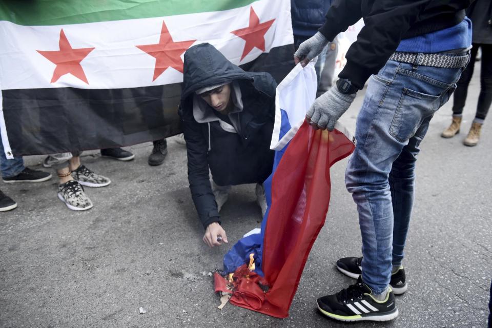 Syrian refugees burn a Russian flag during a protest near the Russian Consulate, at the northern Greek city of Thessaloniki, Wednesday, Dec. 14, 2016. A few dozens of Syrian refugees, who live in camps around the city, staged a rally to protest against Russia's military interference in Syria. (AP Photo/Giannis Papanikos)