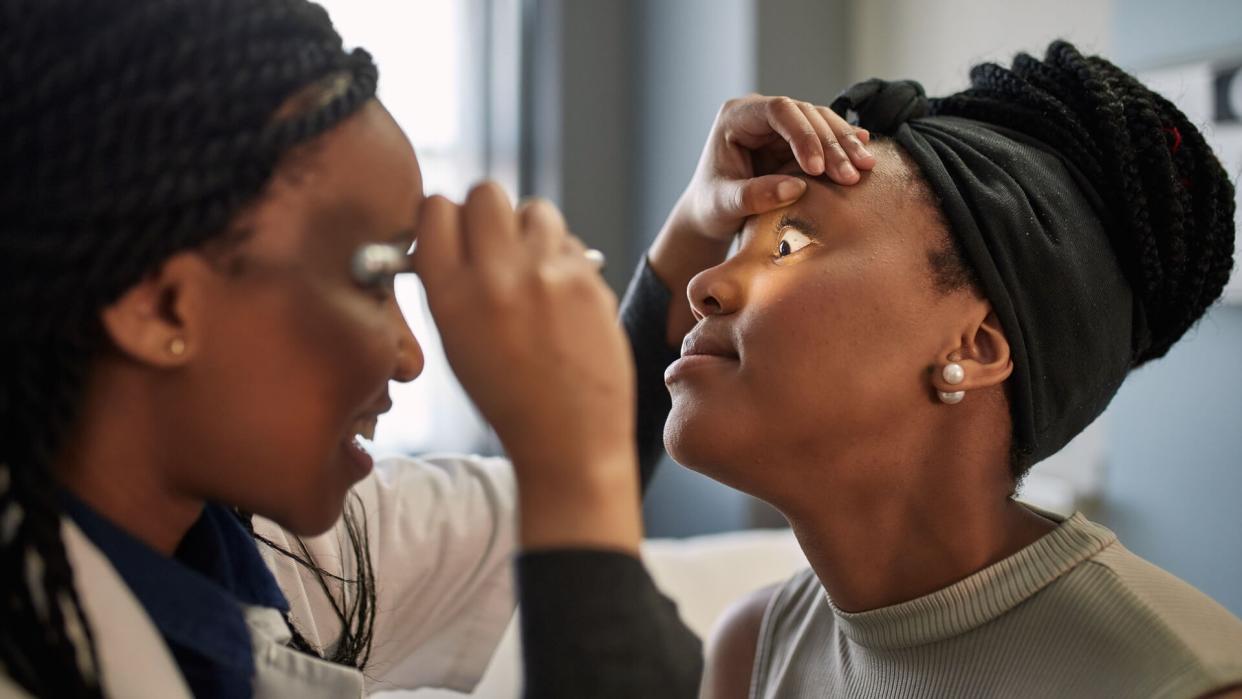 Female doctor checking young patient's eye.