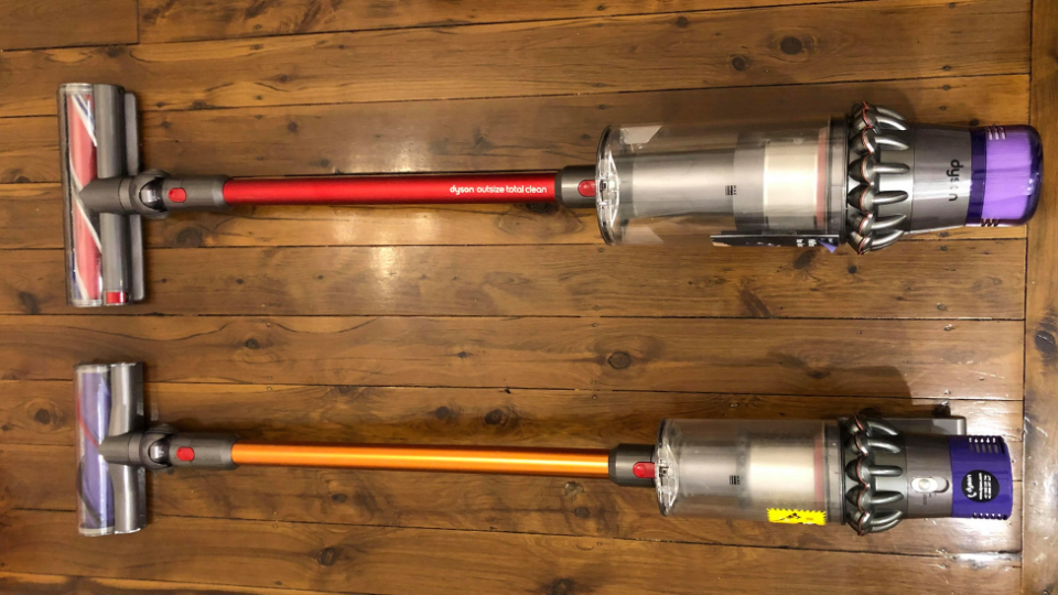 The Dyson Outsize Total Clean stick vacuum laying down next to a Dyson v10 absolute plus stick vacuum to compare the sizes