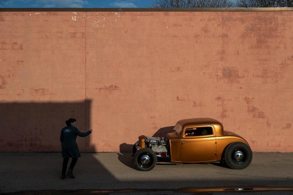 Autumn Riggle directs Logan Kucharek who drives a 1932 Ford with flathead V8 engine into a position for photo in Troy on March 1, 2022.