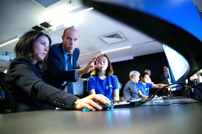 Annalena Baerbock German Foreign Minister, is given a demonstration of a cyber exercise by Matthew Salier, Managing Director of the Australian Center for Cyber Cooperation, and students. Foreign Minister Baerbock's week-long trip to Australia, New Zealand and Fiji will focus on security policy and climate protection. Sina Schuldt/dpa