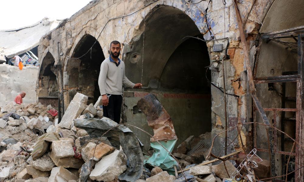 A Syrian man stands among heavily damaged buildings