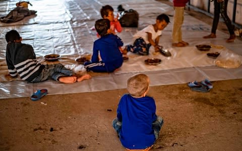 Orphans of foreign Isil fighters gather to eat at a camp in the northern Syrian village of Ain Issa before the women detained there escaped on Sunday - Credit: BBC