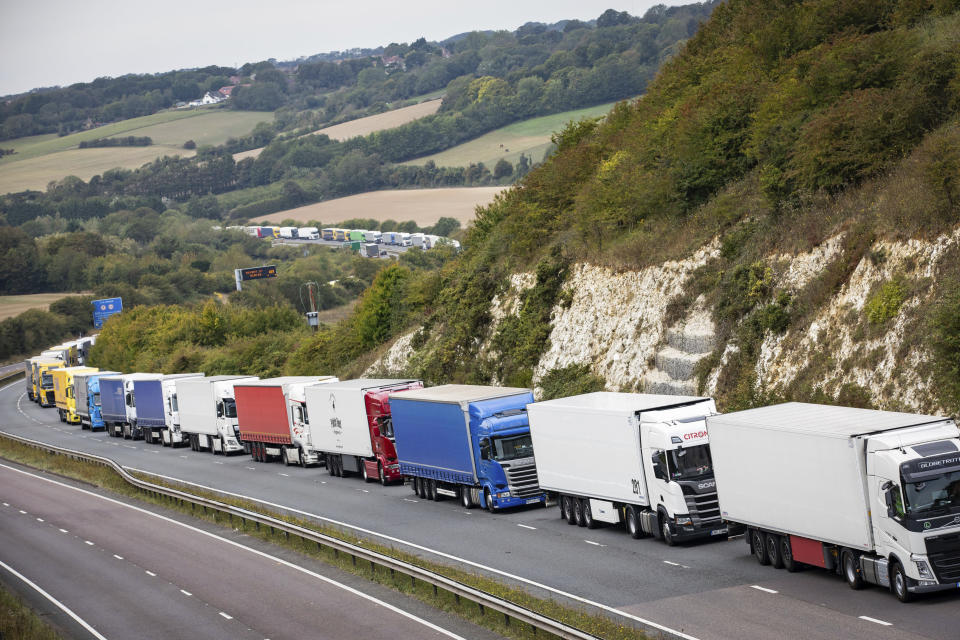 Heavy goods vehicles queue on a main road near Dover, southern England, after a police operation in the port city resulted in traffic congestion on nearby roads, Wednesday Sept. 16, 2020.  Authorities deployed the planned Operation Stack along main roads to cope with heavy traffic approaching the channel port to transit to mainland Europe.  (Aaron Chown/PA via AP)