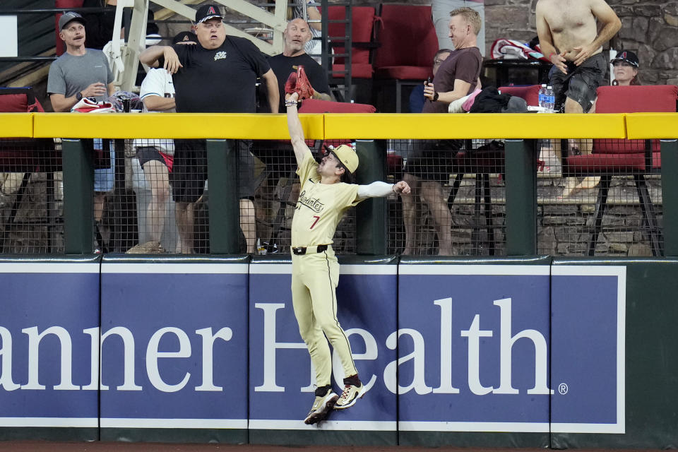 Arizona Diamondbacks right fielder Corbin Carroll reaches over the fence to make a catch on a fly ball hit by San Francisco Giants' Mike Yastrzemski during the second inning of a baseball game Tuesday, Sept. 24, 2024, in Phoenix. (AP Photo/Ross D. Franklin)