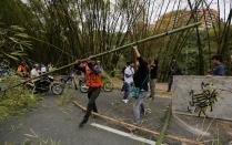 Un motociclista remueve cañas de bambú colocadas para bloquear una calle mientras un manifestante trata de impedírselo en el barrio El Cigarral de Caracas, Venezuela, el lunes 24 de febrero de 2014. La capital venezolana amaneció el lunes en medio de nuevas tensiones luego de que decenas de manifestantes bloquearon algunas de las principales avenidas en protesta contra el gobierno, en medio de la crisis política que lleva tres semanas y ha dejado 11 muertos y más de un centenar de heridos.(AP foto/Fernando Llano)