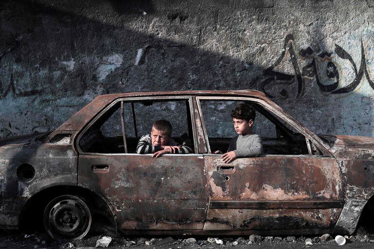Chicos palestinos en un auto destruido en Rafah, en el sur de la Franja de Gaza. (AFP)