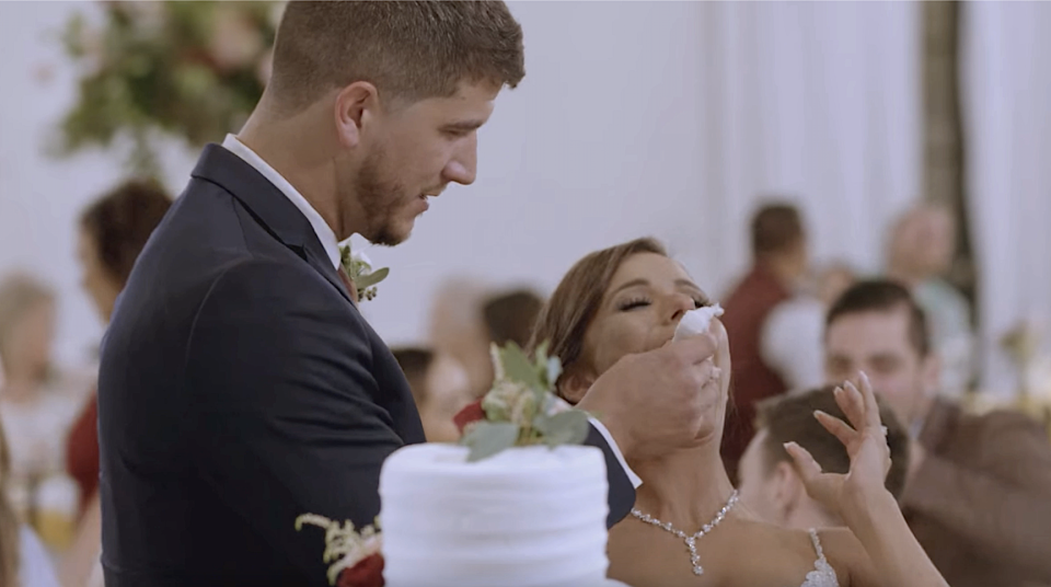 A groom feeding his bride cake