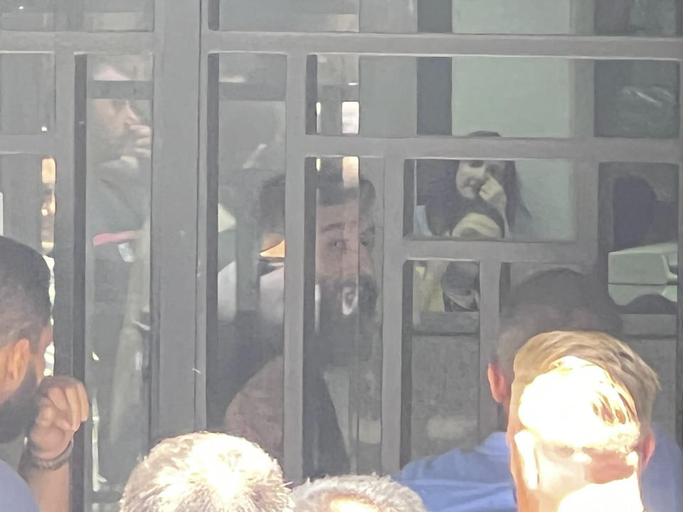 A man shouts inside the bank as he holds hostages at gunpoint in Beirut,, Lebanon, Thursday, Aug. 11, 2022. A Lebanese security official says a man armed with a shotgun has broken into a Beirut bank, holding employees hostage and threatening to set himself ablaze with gasoline unless he receives his trapped saving. (AP Photo/Hussein Malla)