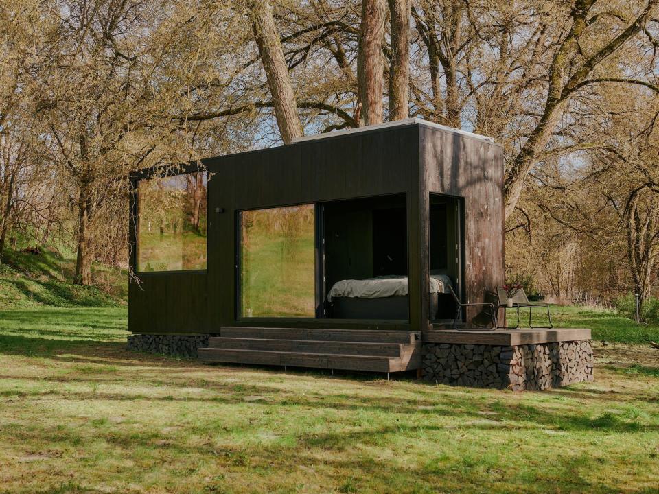 A Raus cabin in nature surrounded by trees and open fields.