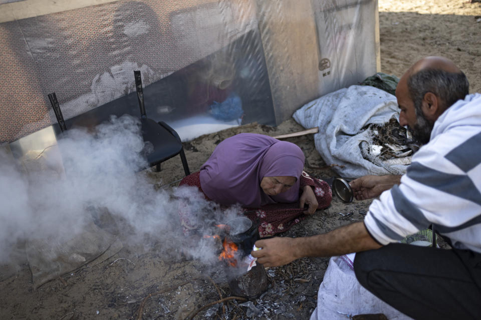 Members of the Abu Jarad family, who were displaced by the Israeli bombardment of the Gaza Strip, make tea at a makeshift tent camp in the Muwasi area, southern Gaza, Monday, Jan. 1, 2024. (AP Photo/Fatima Shbair)