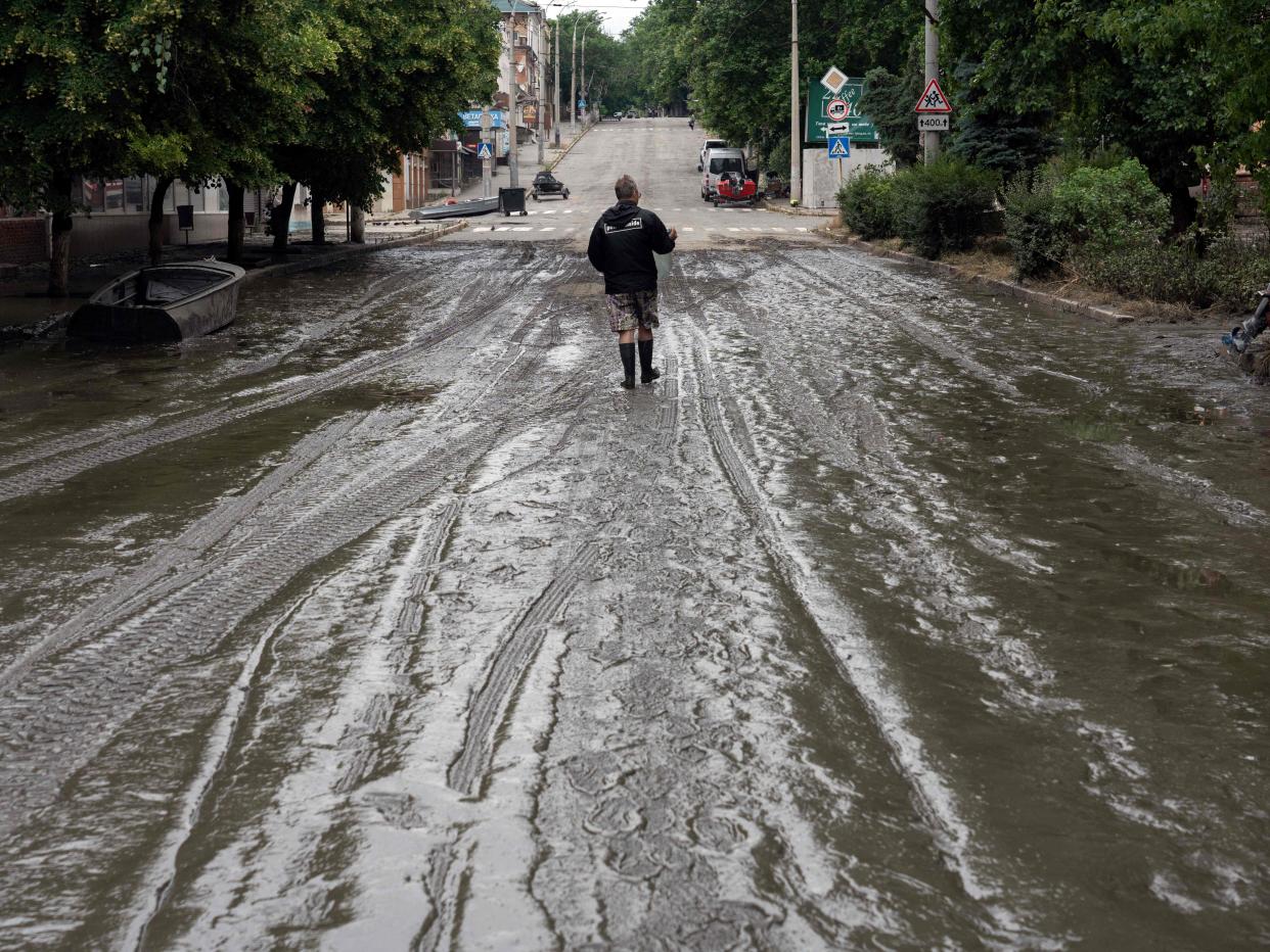 A local resident walks through a muddy street after the flood in Kherson following damages sustained at Kakhovka hydroelectric power plant dam (AFP via Getty Images)