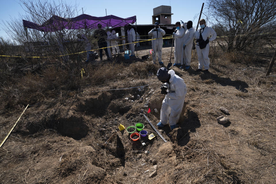 Forensic technicians excavate a field on a plot of land referred to as a cartel "extermination site" where burned human remains are buried, on the outskirts of Nuevo Laredo, Mexico, Tuesday, Feb. 8, 2022. After six months of work, there are still more than 30,000 square feet of property to inspect and catalog. (AP Photo/Marco Ugarte)