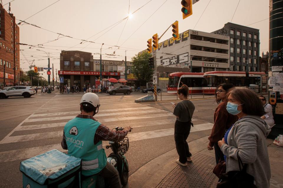 People make their way through a gloomy atmosphere in Toronto on June 5, 2023. Poor air quality across Southern Ontario is the result of wildfires burning across the country.