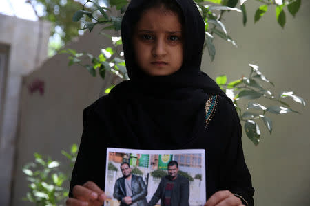 Farah, daughter of Walid al-Abidi, who was killed by Islamic State militants at Kirkuk road, holds his picture, in Kerbala, Iraq July 5, 2018. Picture taken July 5, 2018. REUTERS/Abdullah Dhiaa al-Deen