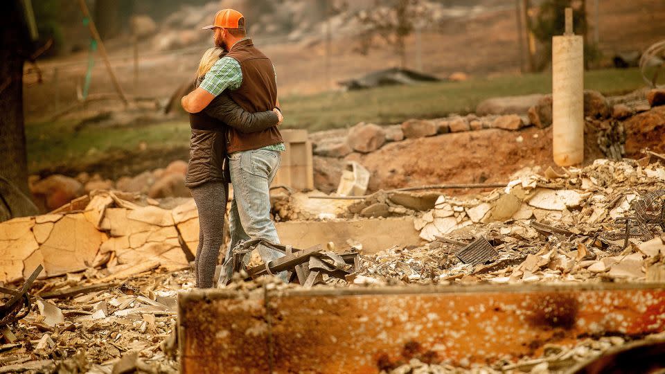 Victims of the Camp Fire embrace while searching through the remains of their Paradise, California, home on November 12, 2018.  - Noah Berger/AP