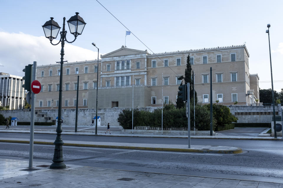 A woman walks in front of the Greek parliament during the first day of a lockdown, in Athens, Saturday, Nov. 7, 2020. With a surge in coronavirus cases straining health systems in many European countries, Greece has announced a three-week nationwide lockdown. (AP Photo/Yorgos Karahalis)