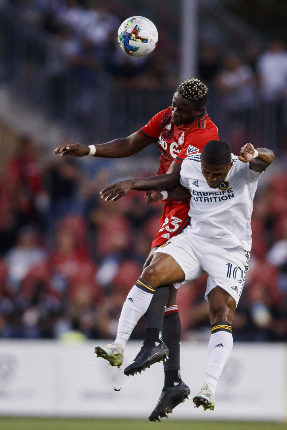 Toronto FC defender Chris Mavinga (23) and LA Galaxy forward Douglas Costa (10) jump for a ball during the first half of an MLS soccer game in Toronto on Wednesday, Aug. 31, 2022. (Cole Burston/The Canadian Press via AP)