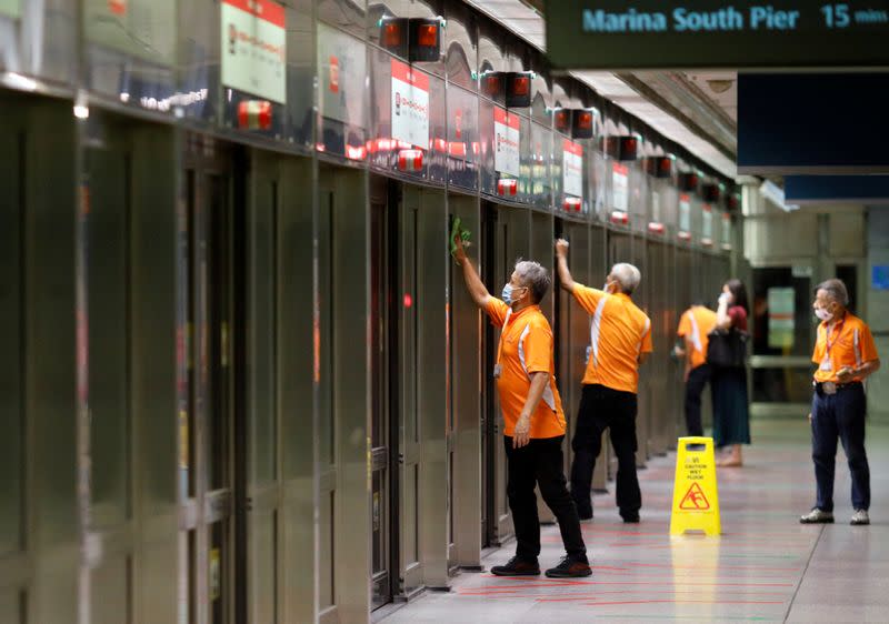 FILE PHOTO: Workers wipe down doors at a train station during the coronavirus disease (COVID-19) outbreak in Singapore