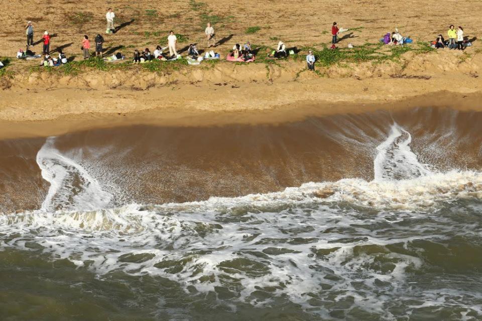 People are seen on the beach front to view the solar eclipse on November 14, 2012 in Palm Cove, Australia.