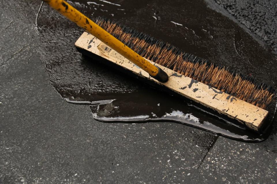 Asphalt driveway sealing with a wide, flat brush