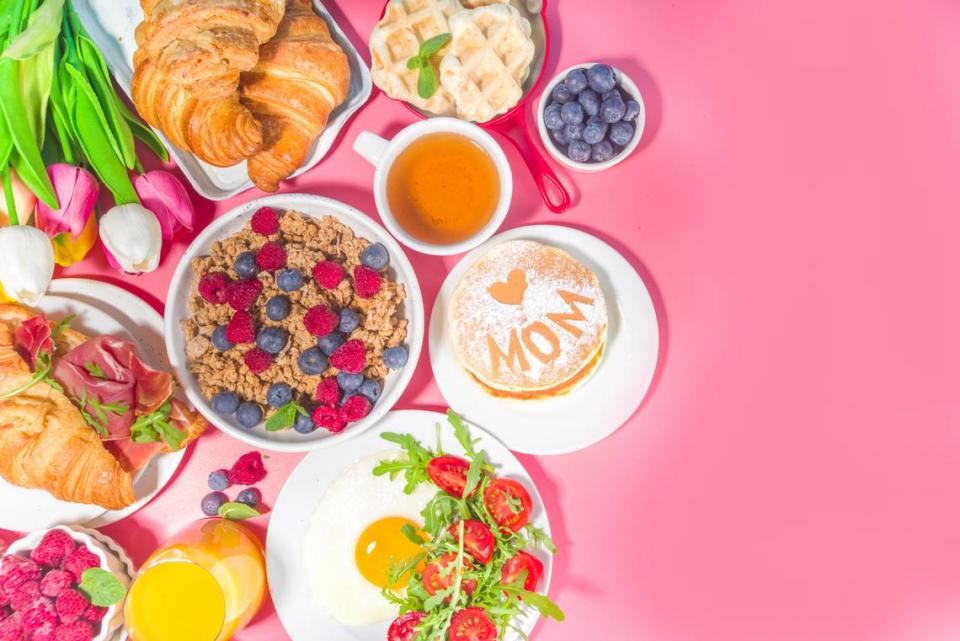 Mothers day Brunch restaurant invitation concept. Various Moms Womans Day Menu background, with traditional breakfast and lunch food and drink set, with flowers on sunny pink background Rimma_Bondarenko/Getty Images/iStockphoto