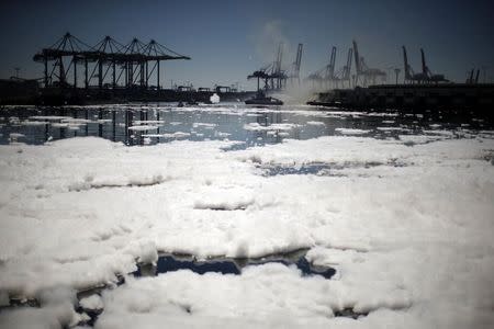 Firefighters douse a smouldering dock fire that broke out on Monday evening and burned about 150 feet (45 meters) of a wharf area at the Port of Los Angeles, as foam swirls around the dock, California September 23, 2014. REUTERS/Lucy Nicholson
