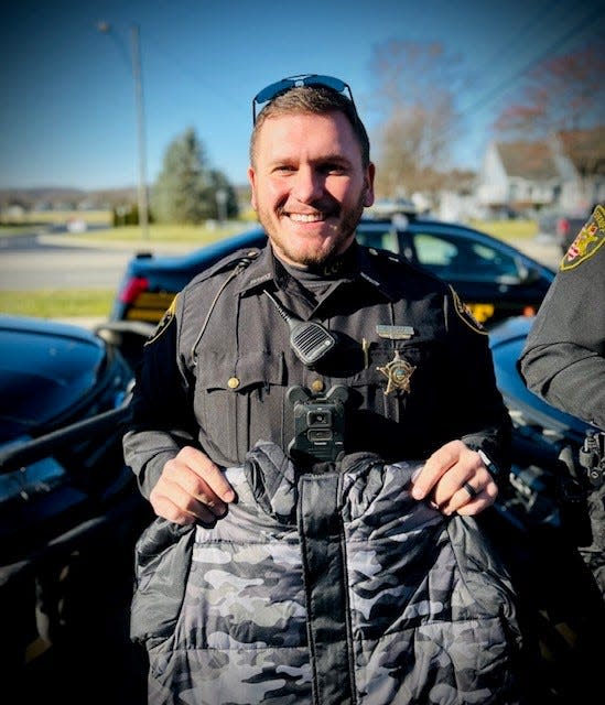 A Licking County deputy holds a coat to be donated to Licking County kids through a partnership with Starfish Assignment of Licking County in December 2022.