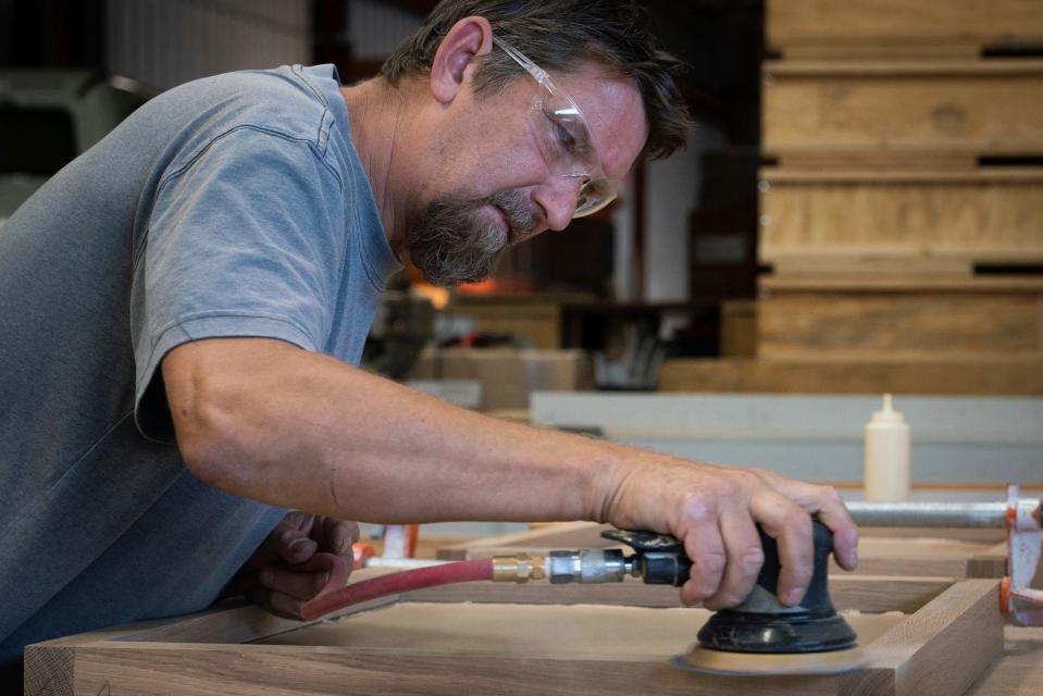 Dan Hefner, 48, lead carpenter, sands a frame for a framing challenge game part of a interactive exhibit on wheels commissioned by the Michigan Regional Council of Carpenters and Millwrights at Creative Solutions Group in Clawson on Thursday, Aug. 31, 2023.
