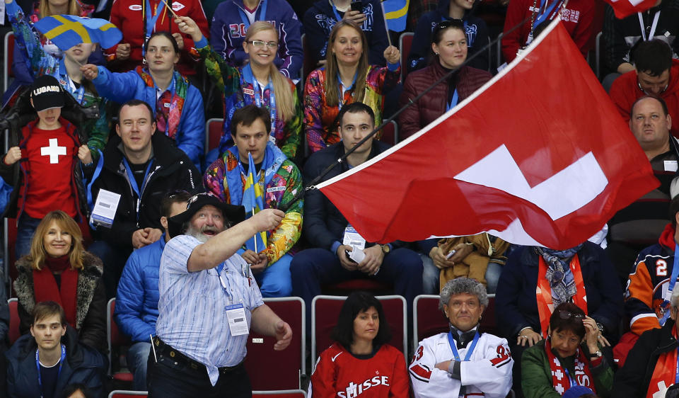 A hockey fan waves a Swiss flag in the first period of a men's ice hockey game between Switzerland and Sweden at the 2014 Winter Olympics, Friday, Feb. 14, 2014, in Sochi, Russia. (AP Photo/Julio Cortez)