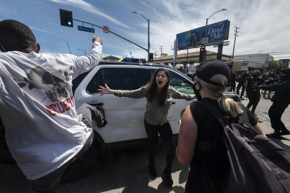 A protester, center, tries to stop others from attacking a police vehicle during a protest over the death of George Floyd in Los Angeles, May 30, 2020. The image was part of a series of photographs by The Associated Press that won the 2021 Pulitzer Prize for breaking news photography. (AP Photo/Ringo H.W. Chiu)