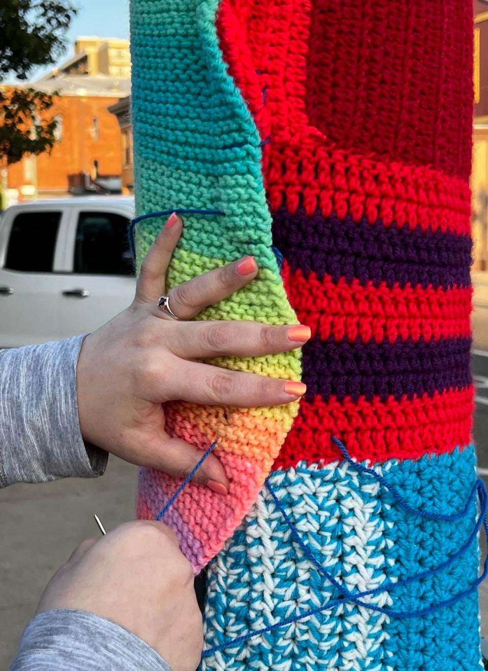 Volunteer Natalie Starn works on yarn art on Sixth Street NW in downtown Canton. A group of volunteers, headed by Vicki Boatright of BZTAT Studios, is installing the yarn pieces on poles and buildings.