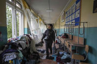 FILE - School official Iryna Homenko walks in the hall of a school damaged by an airstrike from Russian forces in Chernihiv, Ukraine, Wednesday, April 13, 2022. In Chernihiv alone, the city council said only seven of the city’s 35 schools were unscathed. Three were reduced to rubble. (AP Photo/Evgeniy Maloletka, File)