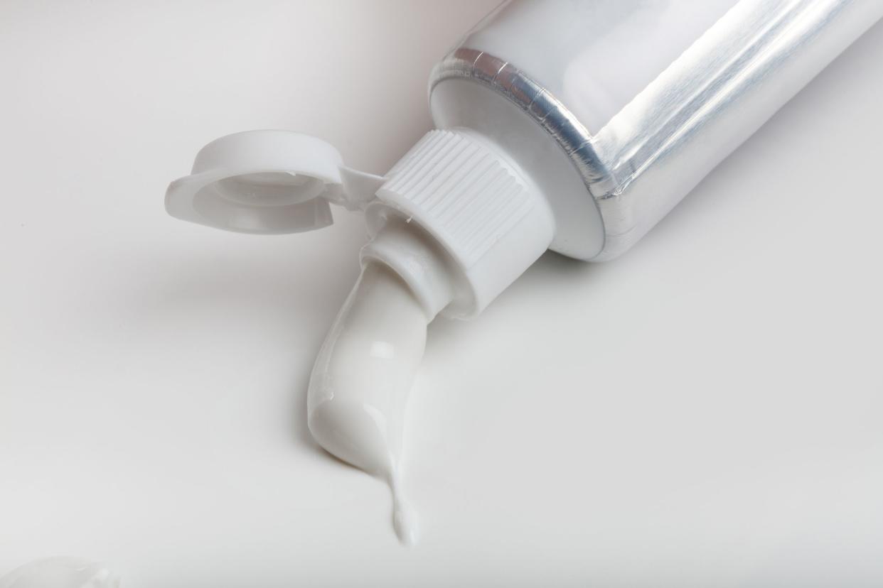 white toothpaste coming out of tube on white background