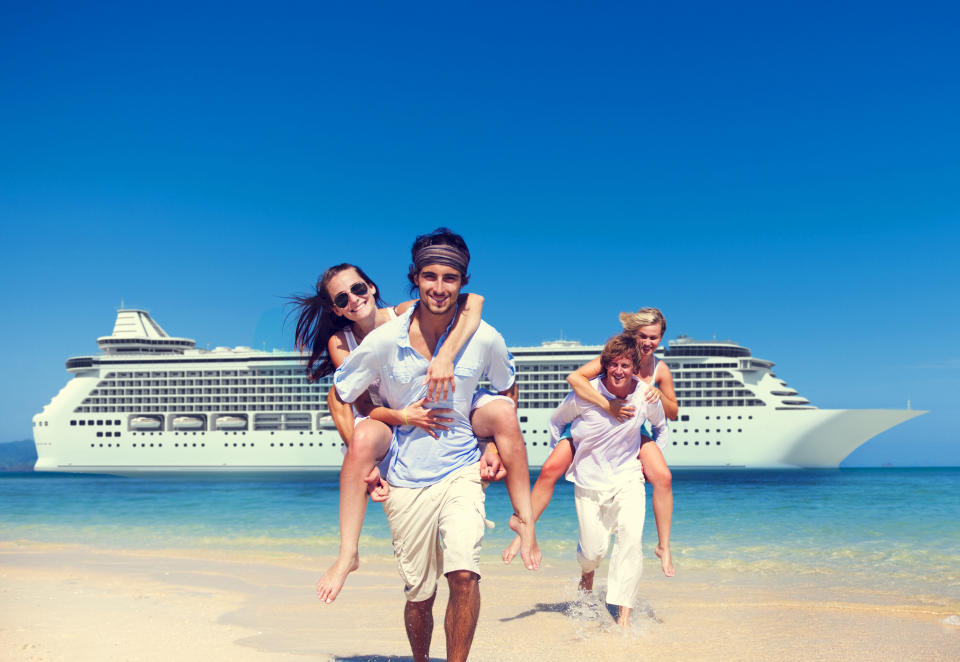 Two couples stand on a beach in front of a cruise ship.