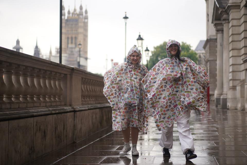 Tourists wear rain ponchoes on Whitehall (PA)
