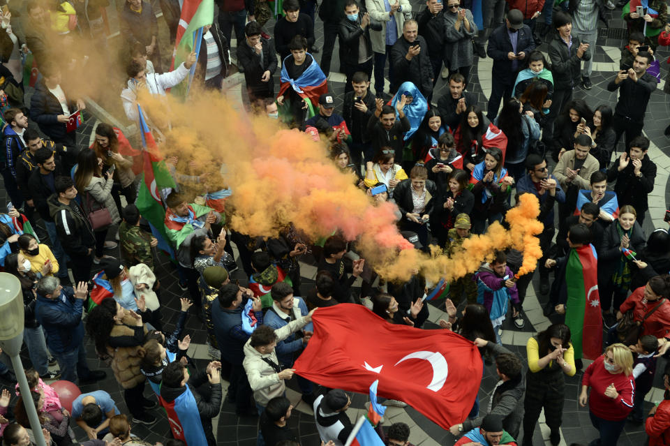 Azerbaijanis celebrate waving national and Turkish flags in Baku, Azerbaijan, Tuesday, Nov. 10, 2020. Armenia and Azerbaijan announced an agreement early Tuesday to halt fighting over the Nagorno-Karabakh region of Azerbaijan under a pact signed with Russia that calls for deployment of nearly 2,000 Russian peacekeepers and territorial concessions. (AP Photo)