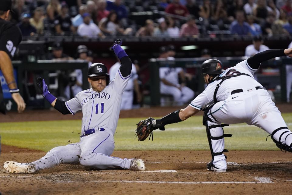 Colorado Rockies' Jose Iglesias (11) scores as Arizona Diamondbacks catcher Carson Kelly attempts to make a tag during the ninth inning of a baseball game Thursday, July 7, 2022, in Phoenix. The Rockies won 4-3. (AP Photo/Ross D. Franklin)