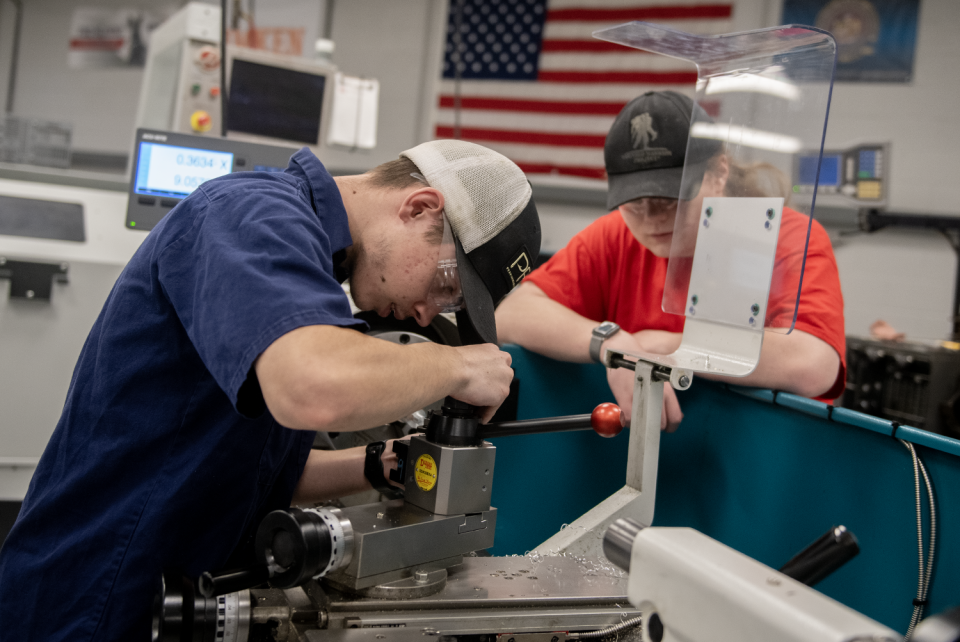 Garrett Bramlett, 18, looks on as Devin Miller, 17, changes a cutter April 11 at Barberton High School.