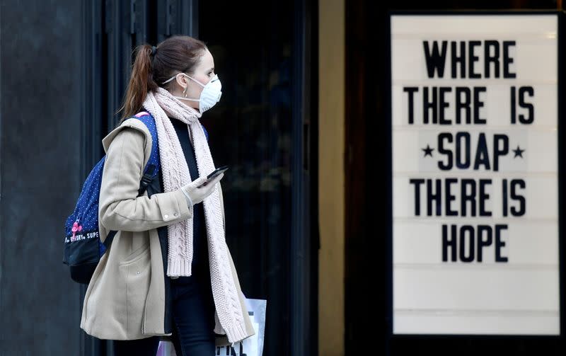 A woman wearing a protective face mask walks past a shop, as the spread of the coronavirus disease (COVID-19) continues, in London