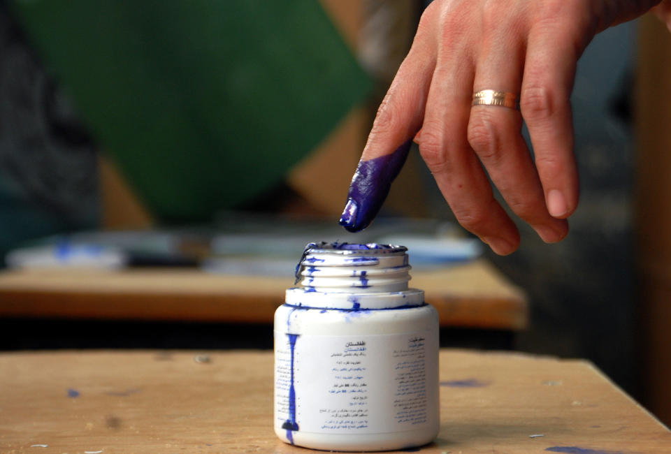 An Afghan woman puts her finger into an ink bottle to mark herself as a voter who attended an election at a polling station in Mazar-i-Sharif, capital of Balkh province, Afghanistan, Saturday, April 5, 2014. (AP Photo/Mustafa Najafizada)