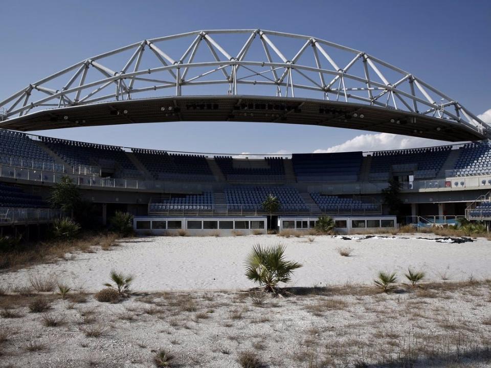 the beach volleyball center where weeds are growing through the sand