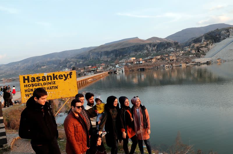 People pose for a souvenir photo by the bridge across the Tigris River in Hasankeyf