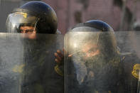 Police stand behind their shield during clashes with anti-government protester in Lima, Peru, Tuesday, Jan. 24, 2023. Protesters are seeking the resignation of President Dina Boluarte, the release from prison of ousted President Pedro Castillo, immediate elections and justice for demonstrators killed in clashes with police. (AP Photo/Martin Mejia)