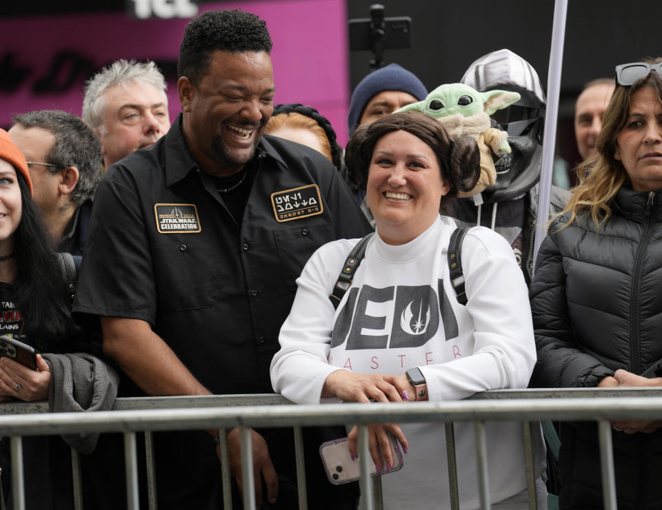 Otis Farrell, izquierda, y Bertha Channell, de Anaheim, California vestidos con disfraces de "Star Wars" esperan en una acera antes de una ceremonia en honor a la fallecida actriz Carrie Fisher quien recibió una estrella póstuma en el Paseo de la Fama de Hollywood el 4 de mayo de 2023. La fecha se conoce también como Día de Star Wars, en homenaje a las películas de "Star Wars" en las que Fisher interpretó a la Princesa Leia. (Foto AP/Chris Pizzello)